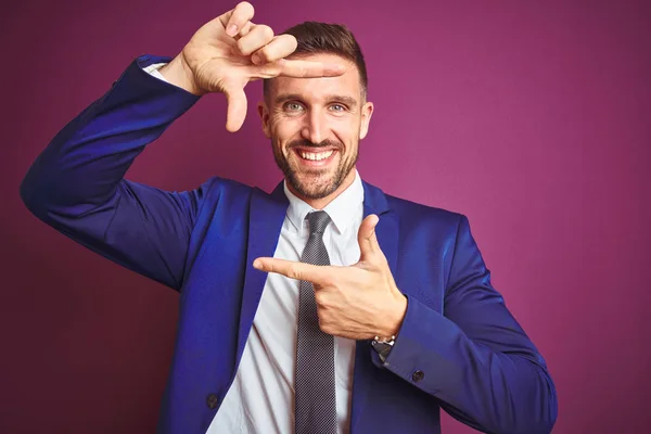 Young handsome business man over purple isolated background smiling making frame with hands and fingers with happy face. Creativity and photography concept.