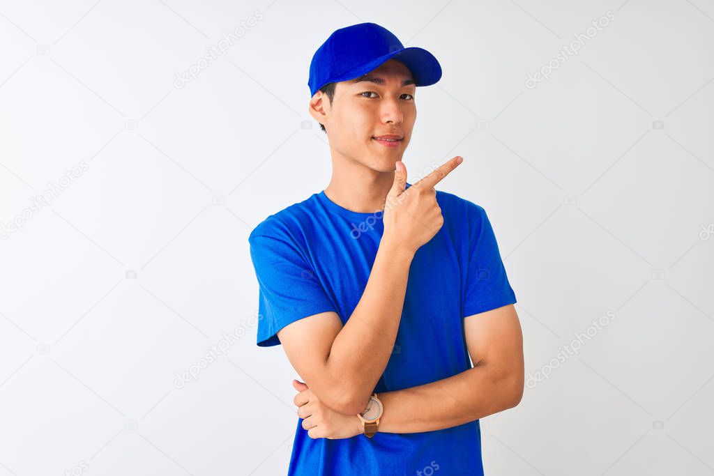 Chinese deliveryman wearing blue t-shirt and cap standing over isolated white background cheerful with a smile of face pointing with hand and finger up to the side with happy and natural expression on face