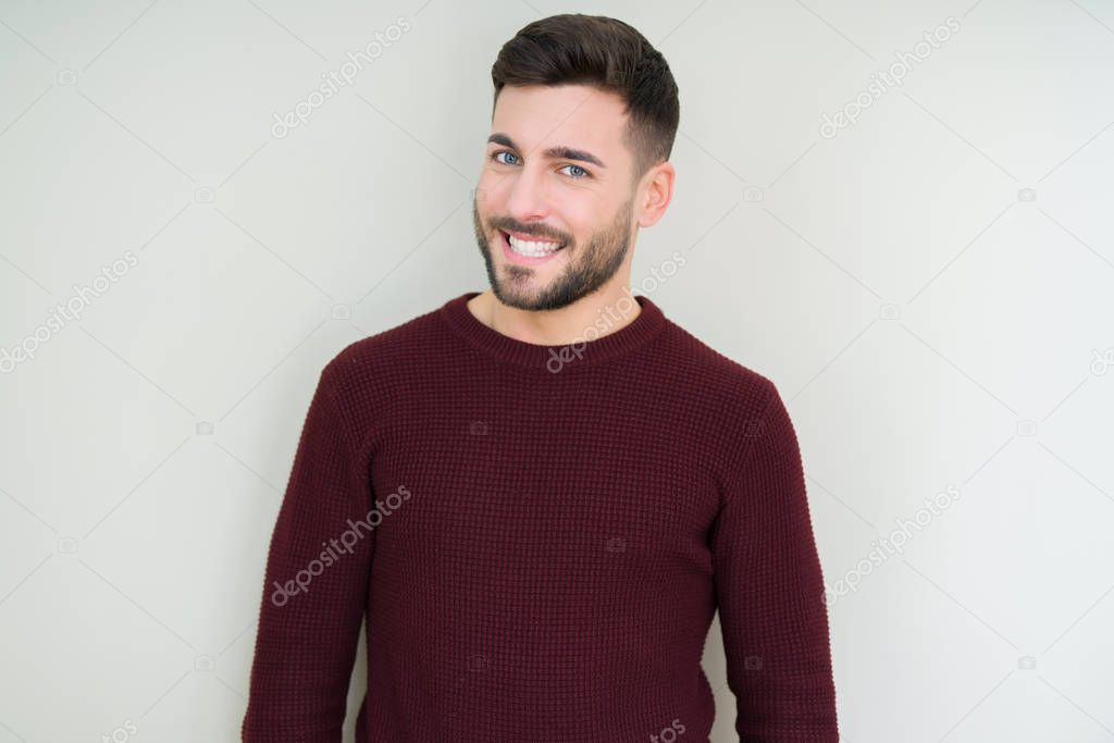 Young handsome man wearing a sweater over isolated background looking away to side with smile on face, natural expression. Laughing confident.