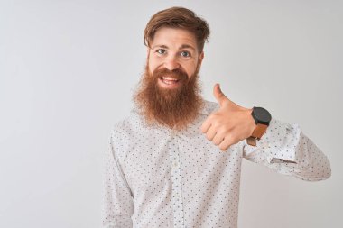 Genç kızıl İrlandalı adam izole beyaz arka plan üzerinde duran gömlek giyen el ile jest kadar mutlu başparmak yapıyor. Başarı göstererek kameraya bakan ifadeyi onaylama.