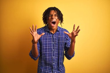 Dreadlocks rahat gömlek giyen afro adam izole sarı arka plan üzerinde ayakta kollarını kaldırdı ve kapalı gözleri heyecanlı çığlık ile başarı için deli ve deli kutluyor. Kazanan kavramı