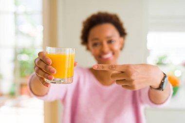 Genç afro-amerikan kadın evde portakal suyu damlayan çok mutlu el ve parmak ile işaret