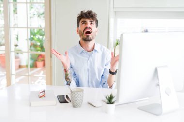 Genç iş adamı bilgisayar deli ve deli kullanarak çalışan bağırarak ve agresif ifade ve silah kaldırdı ile bağırıyor. Hayal kırıklığı kavramı.