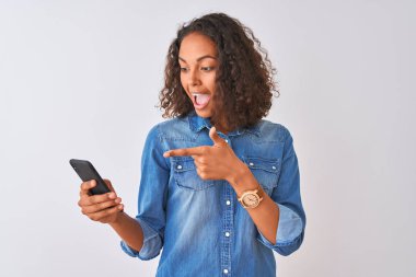 Genç Brezilyalı kadın izole beyaz arka plan üzerinde duran akıllı telefon kullanarak çok mutlu el ve parmak ile işaret