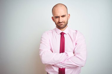 Genç iş adamı izole arka plan şüpheci ve sinir üzerinde pembe kravat giyen, çapraz kolları ile yüzünde onaylamayan ifade. Negatif kişi.
