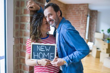 Orta yaş Senior çift yeni bir eve hareket, yeni bir ev metin ile bir tahta tutan Apartmant aşık mutlu gülümseyen
