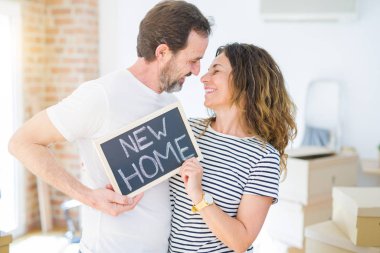 Orta yaş Senior çift yeni bir eve hareket, yeni bir ev metin ile bir tahta tutan Apartmant aşık mutlu gülümseyen