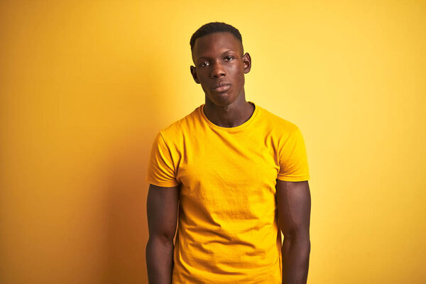 Young african american man wearing casual t-shirt standing over isolated yellow background looking sleepy and tired, exhausted for fatigue and hangover, lazy eyes in the morning.