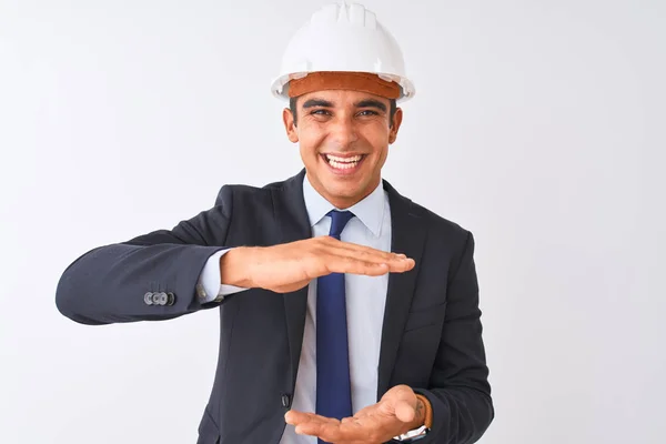 年轻英俊的建筑师男子穿着西装和头盔在孤立的白色背景手势与双手显示大尺寸的标志 测量符号 微笑着看着相机 测量概念 — 图库照片