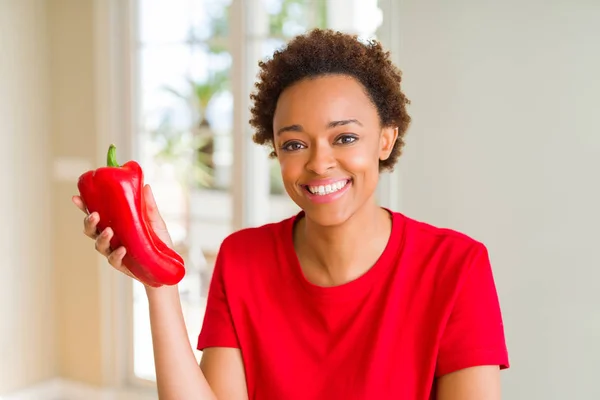 幸せな顔をした新鮮な赤こしょうを持つ若いアフリカ系アメリカ人女性が 歯を見せる自信に満ちた笑顔で立ち上がり 微笑んでいる — ストック写真