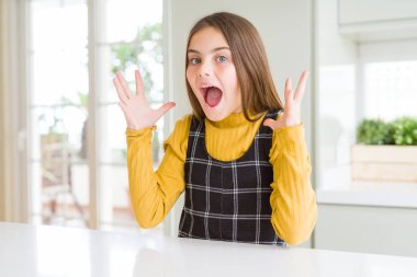 Genç güzel sarışın çocuk kız evde rahat sarı kazak giyen deli kutluyor ve kollarını kaldırdı ve açık gözleri heyecan çığlık ile başarı için hayran. Kazanan kavramı