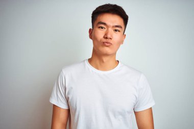 Genç asyalı Çinli adam izole beyaz arka plan üzerinde duran t-shirt giyen kamera hava güzel ve seksi olmak bir öpücük üfleme bakarak. Aşk ifadesi.