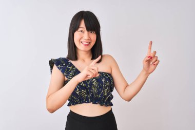 Genç güzel Çinli kadın izole beyaz arka plan üzerinde yaz çiçek t-shirt giyen gülümseyerek ve yan iki el ve parmakları ile işaret kamera bakıyor.