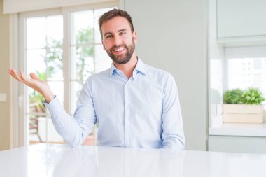 Yakışıklı iş adamı gülümseyerek neşeli sunan ve kameraya bakarak avuç içi ile işaret.