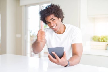 Büyük bir gülümseme ok işareti yapıyor ile mutlu touchpad masa kullanarak Afrikalı Amerikalı adam, parmakları ile başparmak, mükemmel işareti