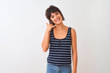 Genç güzel kadın çizgili t-shirt izole beyaz arka plan üzerinde duran giyen telefonda konuşurken gibi el ve parmakları ile telefon jest yapıyor gülümseyerek. İletişim kavramları.