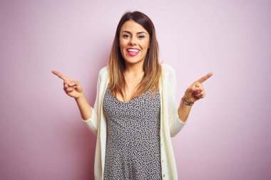 Genç güzel kadın pembe izole arka plan üzerinde duran farklı yönlere parmakları ile işaret güvenerek. Reklam için kopya alanı