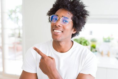 Afrika kökenli Amerikalı adam neşeli bir gülümseme ile el ve parmak kadar yan yüzünde mutlu ve doğal ifade ile işaret yüz ile gözlüklü
