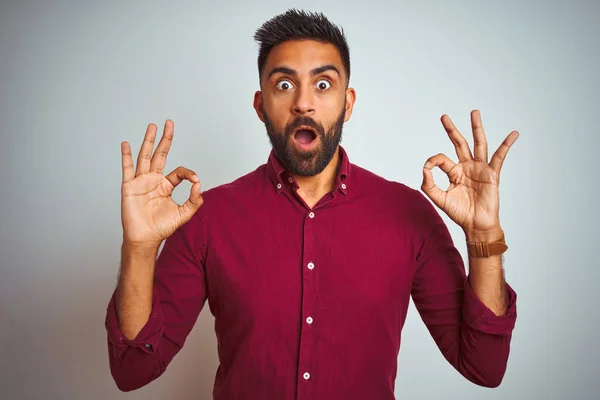 年轻的印度男子穿着红色优雅的衬衫站在孤立的灰色背景 看着惊讶和震惊做确定批准符号用手指 疯狂的表达 — 图库照片