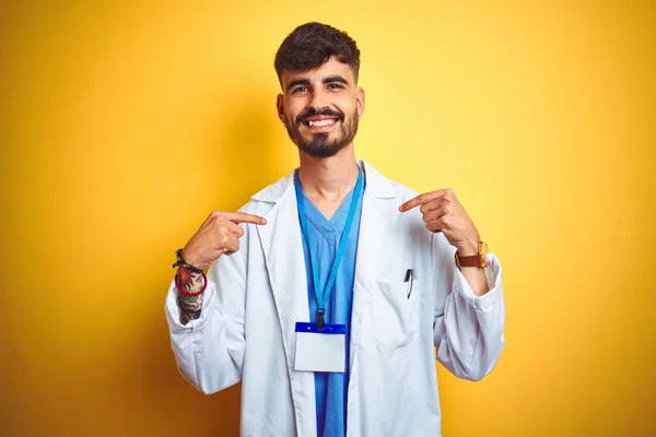 Junger Arzt Mit Tätowierung Der Einen Ausweis Auf Gelbem Hintergrund — Stockfoto