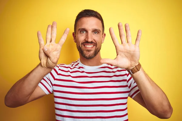 年轻的帅哥穿着休闲的红色条纹T恤在黄色孤立的背景显示和指向手指9号 同时微笑自信和快乐 — 图库照片
