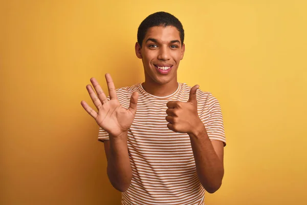 年轻的英俊阿拉伯男子穿着条纹T恤站在孤立的黄色背景显示和指着手指六 同时微笑自信和快乐 — 图库照片