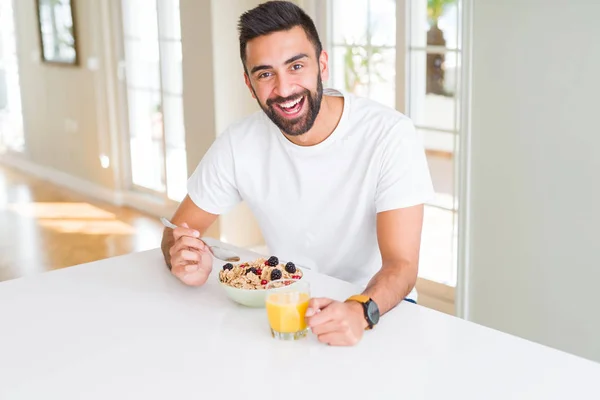 Hombre guapo sonriendo comiendo desayuno saludable y bebiendo orang — Foto de Stock