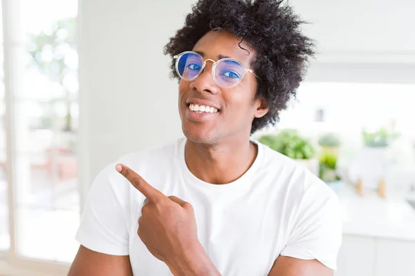 African American man wearing glasses cheerful with a smile of face pointing with hand and finger up to the side with happy and natural expression on face