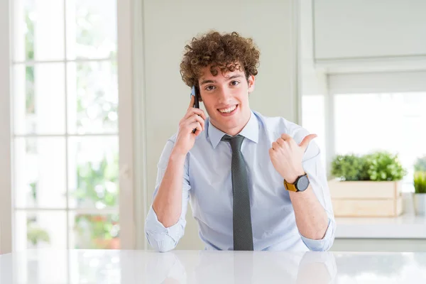 Молодой Бизнесмен Говорящий Смартфону Офисе Показывая Пальцем Вверх Сторону Счастливым — стоковое фото
