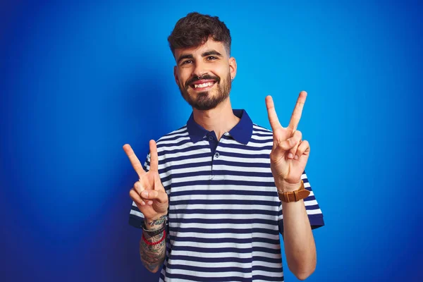 Junger Mann Mit Tätowierung Gestreiftem Polo Der Vor Isoliertem Blauem — Stockfoto