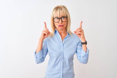 Orta yaş iş kadını izole beyaz arka plan üzerinde zarif gömlek ve gözlük giyen üzgün ve üzgün görünümlü kadar işaret, parmakları ile yön gösteren, mutsuz ve depresif.