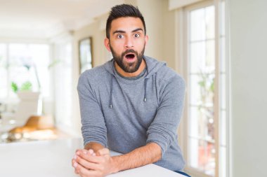 Yakışıklı İspanyol adam evde rahat sweatshirt giyen korkmuş ve sürpriz ifade ile şok, korku ve heyecanlı yüz.