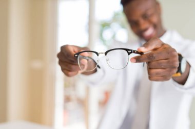 Holding ve gözlük lens Optik dükkanında custumers emin gülümseyen sırasında gösterilen bir Afro-Amerikan optiian adam