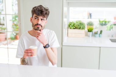 Genç adam sabah bir kağıt fincan bir kahve içme ciddi yüz soru hakkında düşünme, çok karışık bir fikir