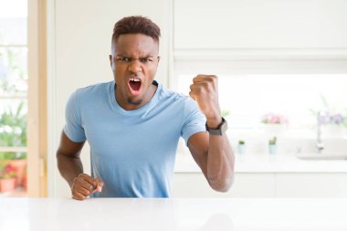 Yakışıklı afro-amerikan adam evde rahat t-shirt giyen kızgın ve öfkeli yükselterek yumruk sinirli ve öfkeli öfke ile bağırırken. Öfke ve agresif kavram.