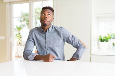 Yakışıklı afro-amerikan adam beyaz masada dudakları, çılgın ve komik jest ile balık yüz yapma. Komik ifade.