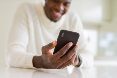 Smarpthone kullanarak ve gülümseyerek Afrikalı iş adamı ellerini yakın