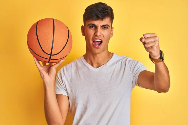 Junger Indischer Sportler Hält Basketballball Vor Isoliertem Gelben Hintergrund Und — Stockfoto