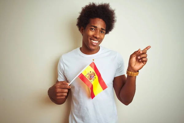 孤立した白い背景の上に立つスペインのスペイン国旗を持つ若いアフロアメリカ人男性は 側に手と指で指差し非常に幸せ — ストック写真