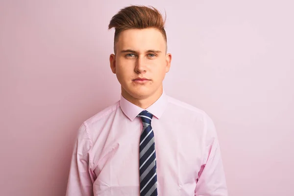 Young handsome businessman wearing shirt and tie standing over isolated pink background Relaxed with serious expression on face. Simple and natural looking at the camera.