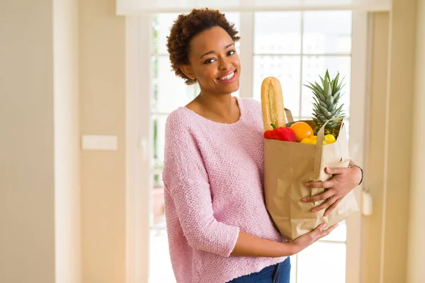 Unga vackra afrikanska amerikanska kvinna som håller papperskasse full av — Stockfoto