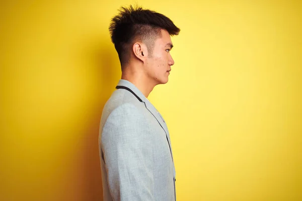 年轻的亚洲华商穿着夹克站在孤立的黄色背景看一边 放松配置文件姿势与自然的脸与自信的笑容 — 图库照片