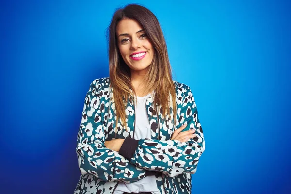 Mavi izole arka plan üzerinde duran bir ceket giyen genç güzel kadın kamera bakarak çapraz kolları ile gülümseyen mutlu yüz. Pozitif kişi.