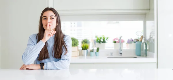 广角图片美丽的年轻女子坐在家里的白色桌子上 要求用手指在嘴唇上安静 沉默和秘密概念 — 图库照片