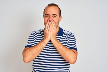 Yalnız beyaz arka plan üzerinde duran rahat çizgili polo giyen genç adam gülerek ve elleri, dedikodu ve skandal kavramı ile ağız kapsayan kıkırdama utandım