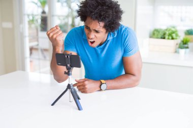 Afro-Amerikan adam akıllı telefon kullanarak web kamerası ile online arama yapıyor kızgın ve sinirli öfke ile bağırarak, deli ve yükseltilmiş el ile bağırıyor, öfke kavramı