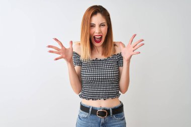 Güzel kızıl saçlı kadın rahat t-shirt izole beyaz arka plan üzerinde deli kutluyor ayakta giyen ve kollarını kaldırdı ve açık gözleri heyecan çığlık ile başarı için hayran. Kazanan kavramı