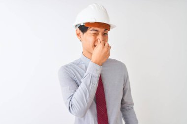 İzole beyaz arka plan üzerinde duran kravat ve kask takan Çinli mimar adam, kokuşmuş ve, dayanılmaz bir koku kokuyor, burnunda parmaklarıyla nefes tutuyor. Kötü kokular kavramı.