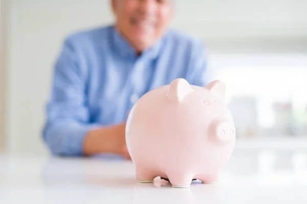 Close up van piggy bank en man die lacht op de achtergrond — Stockfoto