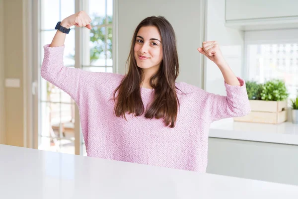 腕の筋肉を誇らしげに示すピンクのセーターを着た美しい若い女性 フィットネスコンセプト — ストック写真